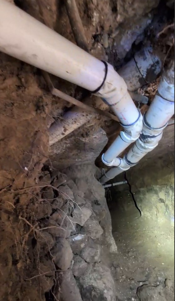 Sewer pipes exposed in excavated trench during repair work - Warren Brothers Plumbing serves Bastrop, Austin, and Elgin TX