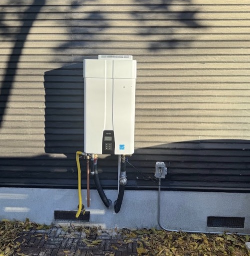 Navien tankless water heater professionally installed on exterior wall - Warren Brothers Plumbing serves Austin, Bastrop, and Central Texas
