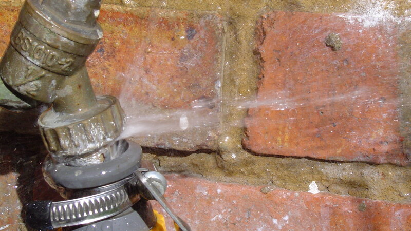 Water spraying from leaking outdoor faucet connection needing repair - Warren Brothers Plumbing serves Bastrop, Austin, and Elgin TX